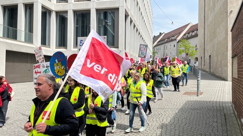 Demonstranten marschieren durch eine Stadt mit Schildern und Ver.di-Fahnen: An den Unikliniken im Land wird gestreikt