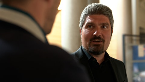 Ein Mann mit graumelliertem Haar unterhält sich mit einer Person: Nebenkläger im Prozess wegen Nachstellung in Langenau war der betroffene Pfarrer der evangelischen Martinskirche, Ralf Sedlak.
