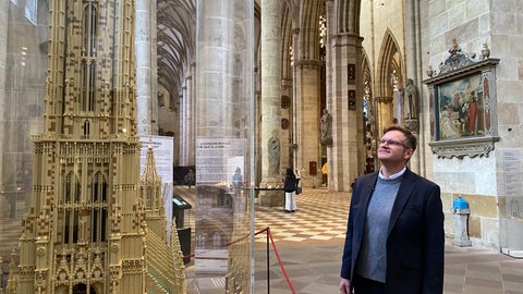 Der Ulmer Münsterpfarrer Julian Scharpf steht vor dem LEGO-Modell des Ulmer Münsters.