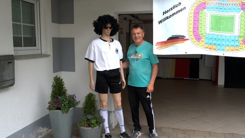 Peter Saß neben einer Schaufensterpuppe mit Perücke, die Franz Beckenbauer darstellen soll.
