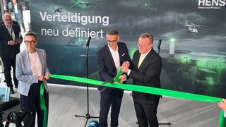 Hensoldt Vorstand Oliver Dörre und Verteidigungsminister Boris Pistorius zerschneiden gemeinsam mit einer großen grünen Schere das Band. Als Zeichen der Eröffnung des neuen Standorts von Hensoldt in Oberkochen.