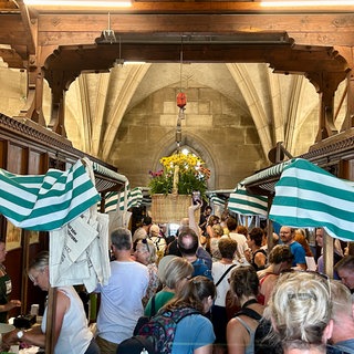 Viele Menschen tummeln sich zwischen den Ständen des Ulmer Wochenmarkts in der Turmhalle des Münsterturms. Elf Händler beteiligen sich am Wochenmarkt im Turm des Ulmer Münsters.