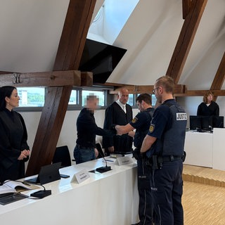 Einem Mann werden im Gerichtssaal die Handschellen abgenommen: Ein Mann muss für vier Jahre in Haft, weil er seinen Arbeitgeber, das Unternehmen Müller, um Millionen Euro betrogen hat. 