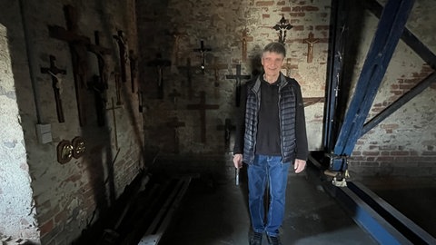 Kreuze hängen an einer alten Wand in einem Kirchturm: In der Georgskirche bekommen alte Kreuze und Kruzifixe eine neue Heimat