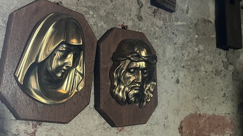 Kreuze hängen an einer alten Wand in einem Kirchturm: In der Georgskirche bekommen alte Kreuze und Kruzifixe eine neue Heimat