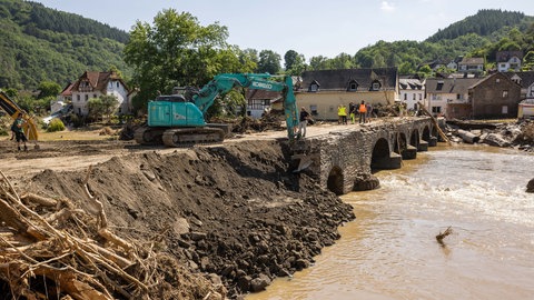 Ein Bagger verdichtet eine notdürftig geflickte Brücke über die Ahr.