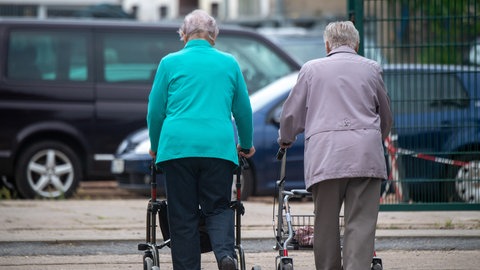 Seniorinnen gehen mit ihrem Rollator durch die Stadt. 