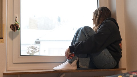 Deprimiert sitzt ein jugendliches Mädchen in ihrem Zimmer. Immer mehr Mädchen unter 14 Jahren melden sich beim Mainzer Frauennotruf.