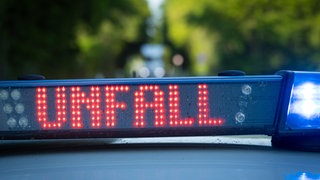 Streifenwagen der Polizei steht mit Blaulicht und dem Schriftzug Unfall im Display an einem Unfallort(Sujetbild). Eine Frau ist in der Nähe der Burg Eltz mit einem Pedelec einen Abhang hinabgestürzt und gestorben.
