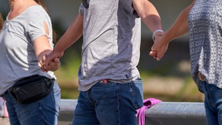 Menschen aus dem Ahrtal halten sich an den Händen - das Miteinander seit der Flutkatastrophe ist in den betroffenen Gebieten sehr groß