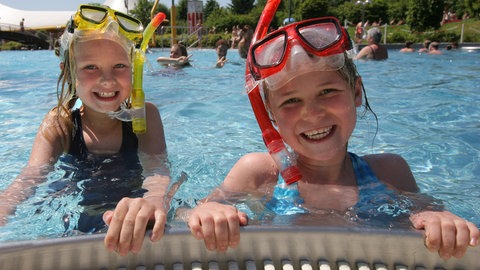 Kinder im Schwimmbad. In den Sommerferien in Rheinland-Pfalz erwartet ARD-Meteorologe Marcel Herber "typisches Sommerwetter". 
