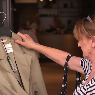 eine Frau betrachtet einen beigen Mantel