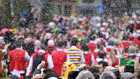 Konfetti fliegt beim Mainzer Rosenmontagszugs von einem Wagen auf die Zuschauer.