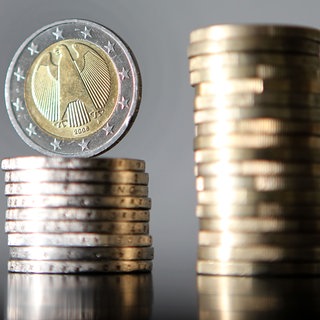 Gestapelte Ein-Euro-Münzen vor neutralem Hintergrund. Die Kommunen in RLP werden laut Landesrechnungshof auch künftig mit Finanzproblemen zu kämpfen haben.