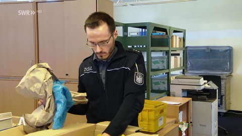Ein Zollmitarbeiter begutachtet ein Paket