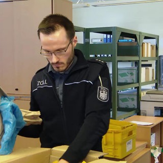 Ein Zollmitarbeiter begutachtet ein Paket
