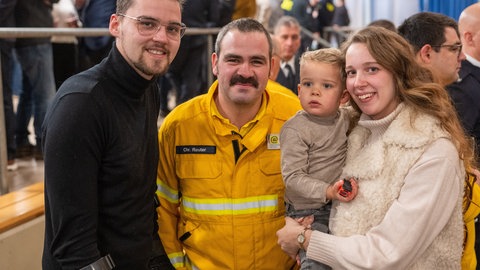 Feuerwehrmann Christoph Reuter (M) steht mit Mark Visser (l), Edi Hoefnagel-Visser und Sohn Jamie beim Neujahrsempfang der Gemeinde Kröv. Reuter war an der Rettung der Familie beteiligt, die im August 2024 beim Einsturz eines Hotel an der Mosel verschüttet wurde.