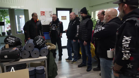 Die Rockergruppe steht im Kreis um die gesammelten Schlafsäcke