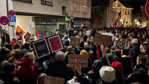 Viele Menschen stehen im Dunkeln auf einem Platz in Landau. Sie sind zu einer Demonstration gegen eine härtere Migrationspolitik zusammengekommen.