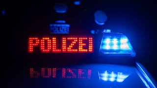 Zwei Polizisten stehen vor einem Polizeifahrzeug (Symbol)
