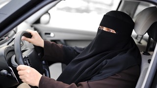Frau fährt Auto mit Gesichtsschleier