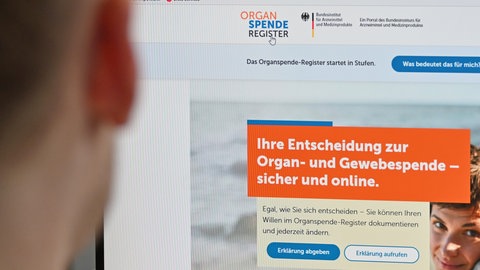 Eine Person sitzt vor einem Bildschirm, auf dem das Online-Portal zur Registrierung zur Organspende zu sehen ist. Seit dem 18. März 2024 können sich Menschen beim digitalen Organspende-Register anmelden, um ihren Willen zur Organspende auszudrücken (Symbolbild)