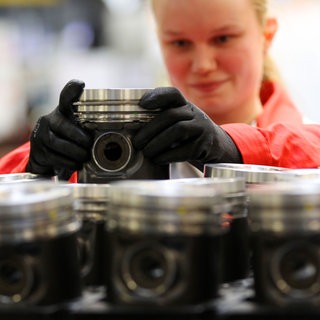 Auszubildende arbeitet an einem Dieselmotor.