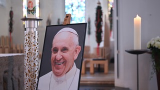 Ein Bild des verstorbenen Papstes Franziskus steht in einer Kirche. Das katholische Kirchenoberhaupt ist am Ostermontag im Alter von 88 Jahren gestorben.