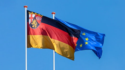 Flaggen von Rheinland-Pfalz und Europa hängen nebeneinander. Das Land profitiert von den Fördergeldern der EU.