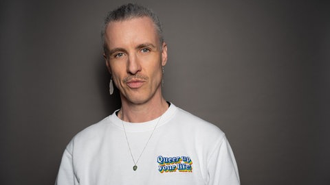 Janboris Ann-Kathrin Rätz trägt einen Pulli mit der Aufschrift "Queer up your live!" und setzt sich als "nicht-binäre Moderator*in" für queere Menschen in RLP ein.