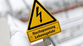 Ein Schild, das vor den Gefahren durch Hochspannungsleitungen warnt. Ein 19-Jähriger ist in Kasbach-Ohlenberg auf einen Waggon geklettert und hat einen tödlichen Stromschlag erlitten.