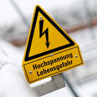 Ein Schild, das vor den Gefahren durch Hochspannungsleitungen warnt. Ein 19-Jähriger ist in Kasbach-Ohlenberg auf einen Waggon geklettert und hat einen tödlichen Stromschlag erlitten.