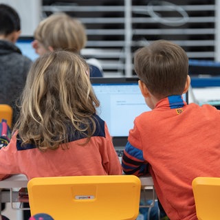 Schüler einer dritten Klasse sitzen vor einem Laptop. Laut einer Umfrage des VBE ist die Inklusion an Schulen in RLP in vielen Bereichen mangelhaft.