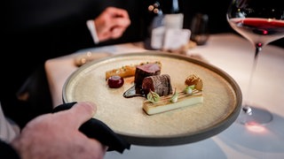 Teller der Spitzen-Gastonomie wird an einen Tisch gebracht. Der Guide Michelin hat seine Sterne vergeben - auch nach RLP.