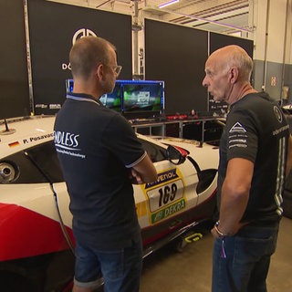 zwei Personen vor einem Rennwagen