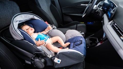 Eine Puppe sitzt für Testzwecke in einem Kindersitz eines Autos, in dem ein KI-System und Sensoren verbaut sind. Ziel ist es, den Hitzetod von Kindern in Fahrzeugen zu verhindern.