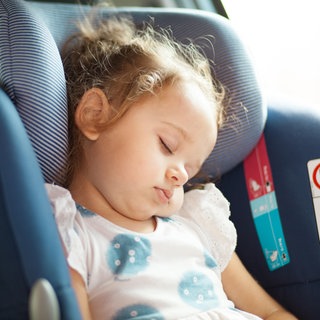 Ein schlafendes Baby in einer Babyschale im Auto. Bei Hitze sollten Kinder auf keinen Fall alleine im Auto gelassen werden. Lebensgefahr.