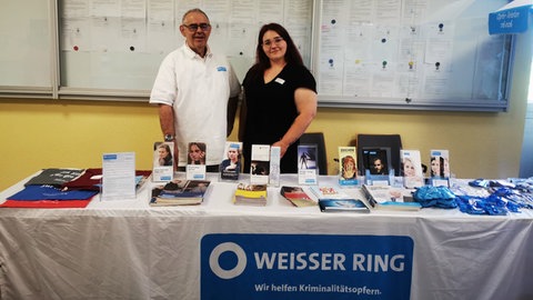 Mareike Luisa Groß und ein Kollege hinter einem Infostand vom Weißen Ring