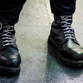 Ein Teilnehmer einer rechtsextremen Kundgebung trägt schwarze Springerstiefel mit weißen Schnürriemen, ein weit verbreitetes Symbol der rechten Szene.