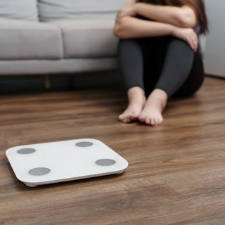 Eine Frau sitzt vor einer Waage. Die Fälle von Essstörungen haben laut Daten der KKH Kaufmännische Krankenkasse bei den 12- bis 17-jährigen Mädchen besonders stark zugenommen. Die Nutzung von Social Media könnte eine Rolle spielen. (Symbolbild)