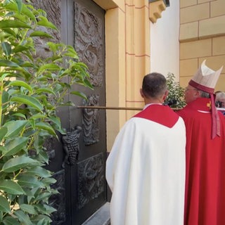 Ein Pfarrer öffnet feierliche die Pforte zu einer Kirche