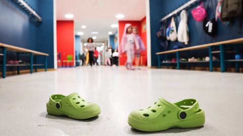 Ein paar grüne Crocs stehen im Flur einer Grundschule, wo die Ganztagsbetreuung bald flächendeckend eingeführt wird.
