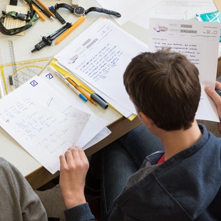 Eine Schülerin und ein Schüler lösen eine Matheaufgabe. Unangemeldete Hausaufgabenprüfungen fallen in RLP künftig weg.