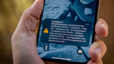 Eine Cell Broadcast Probewarnung, eine Textmeldung, begleitet von einem Alarmton, erscheint auf einem Smartphone-Display.