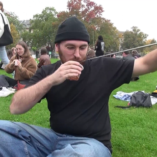 Junger Mann isst Pudding mit einer sehr langen Gabel