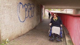 Eine Frau im Rollstuhl durchfährt eine Unterführung