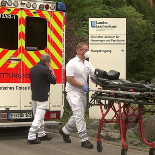 Sanitäter vor einem Rettungswagen mit einer Krankenliege