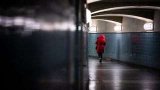Eine Frau in einer roten Jacke läuft alleine durch eine Unterführung. Viele Frauen fühlen sich an solchen Orten unsicher.