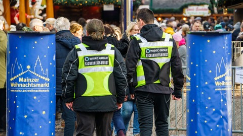 Ein Sicherheitsdienst patrouilliert auf dem Weihnachtsmarkt in Mainz. Der Markt wird in diesem Jahr hermetisch abgeriegelt