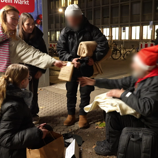 Junge Menschen der youncaritas in Mainz verteilen Decken und Tee an Obachlose.